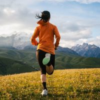 Žena koja džogira u planinskom predelu, vide se vrhovi planina.