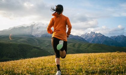 Žena koja džogira u planinskom predelu, vide se vrhovi planina.
