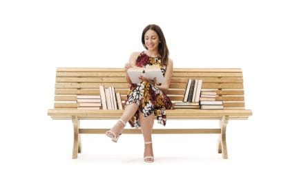 Žena koja sedi na klupi, okružena sa puno knjiga... Jednu drži u ruci, izgleda bira...