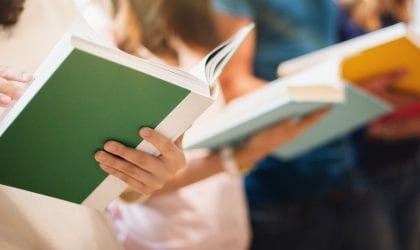 Ženske ruke, drže knjige i prelistavaju.