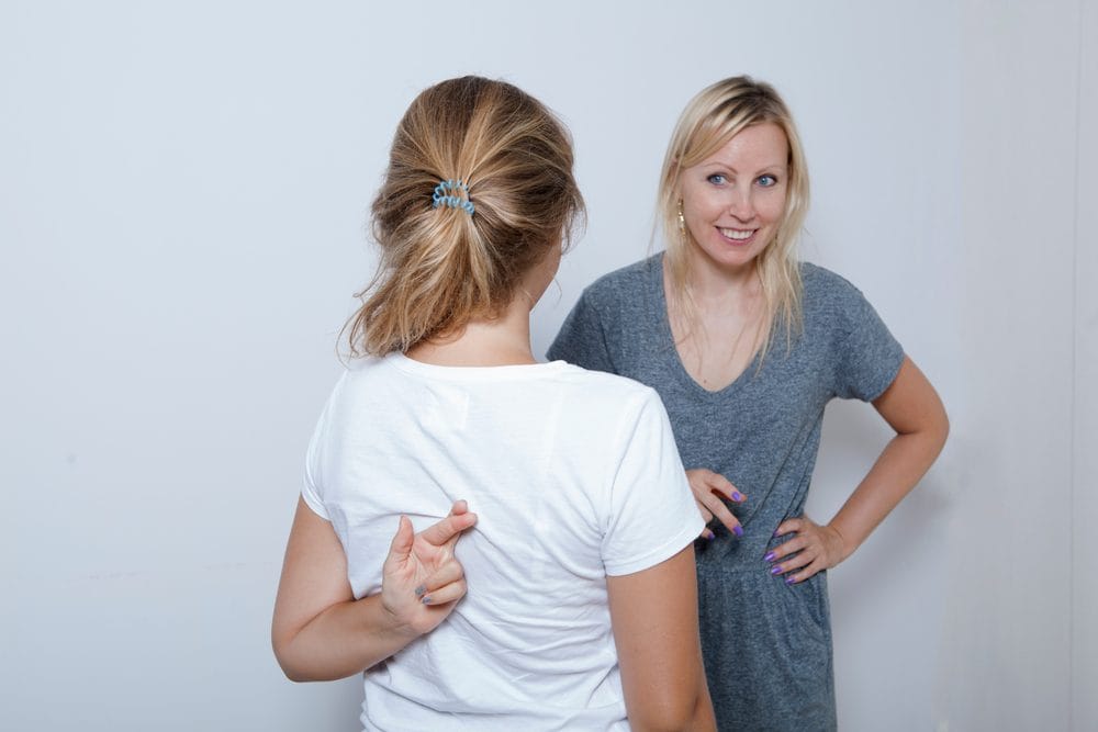 Devojčica izgleda poku&scaron;ava da slaže majku koja nepoverljivo gleda, a devojčica iza leđa drži ukr&scaron;tene prste, moleći se da laž prođe.