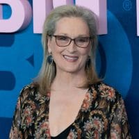 Meril Strip u cvetnoj haljini, nosi naočare za vid sa tamnim okvirima. Portret.