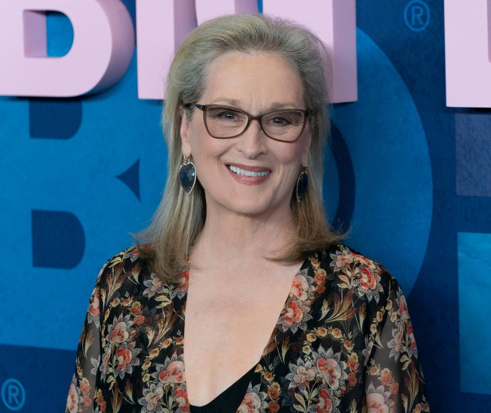 Meril Strip u cvetnoj haljini, nosi naočare za vid sa tamnim okvirima. Portret.