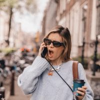 Žena na ulici priča telefonom, viče, ljuti se, neki je problem u pitanju.