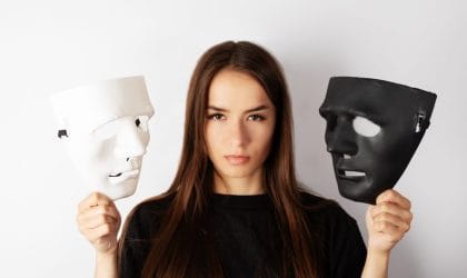 Žena koja u jednoj ruci drži belu masku, a u drugoj crnu.