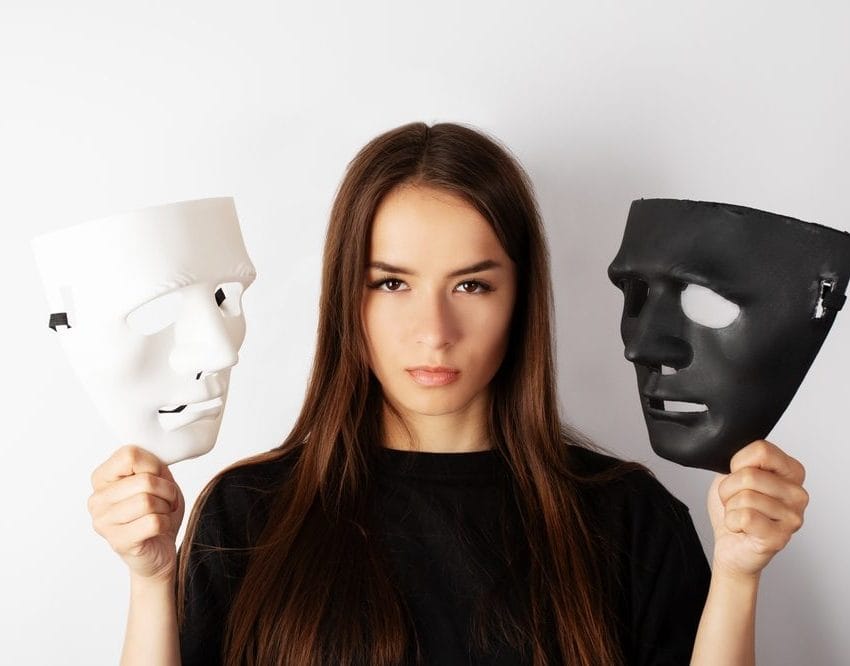 Žena koja u jednoj ruci drži belu masku, a u drugoj crnu.