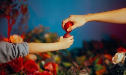 Mama i dete se kucaju jcrvenim jajim za Uskrs.