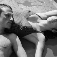 Muškarac i žena leže na plaži u kupaćim kostimima.