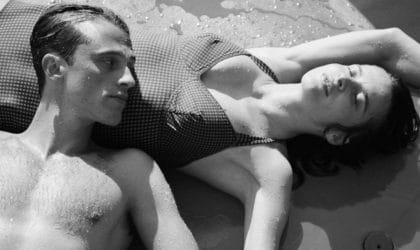 Muškarac i žena leže na plaži u kupaćim kostimima.