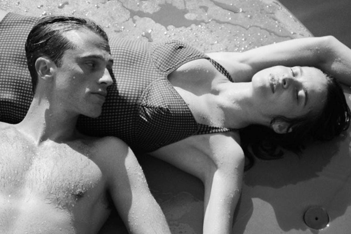 Muškarac i žena leže na plaži u kupaćim kostimima.