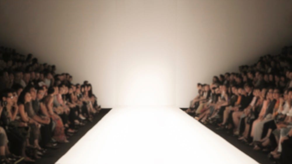 Modna revija, publika je sa obe strane,čeka početak. Pista je dobro osvetljena.