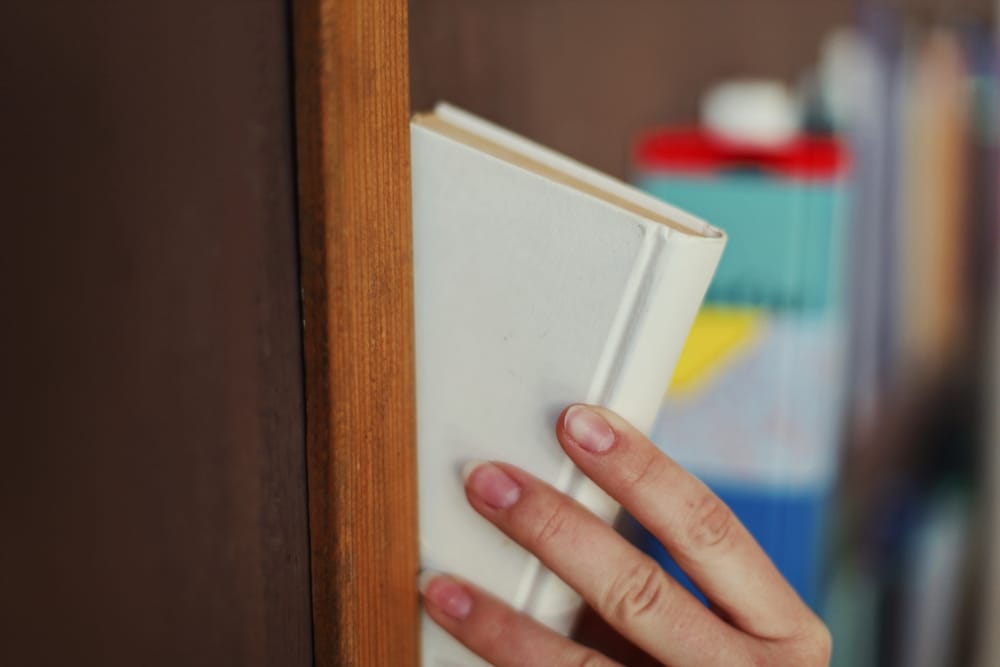 Ženska ruka vadi knjigu iz biblioteke.