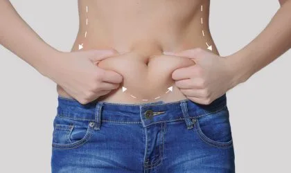 Žena u farmerkama, gornji deo tela je go, rukama drži salo koje se formiralo na stomaku.