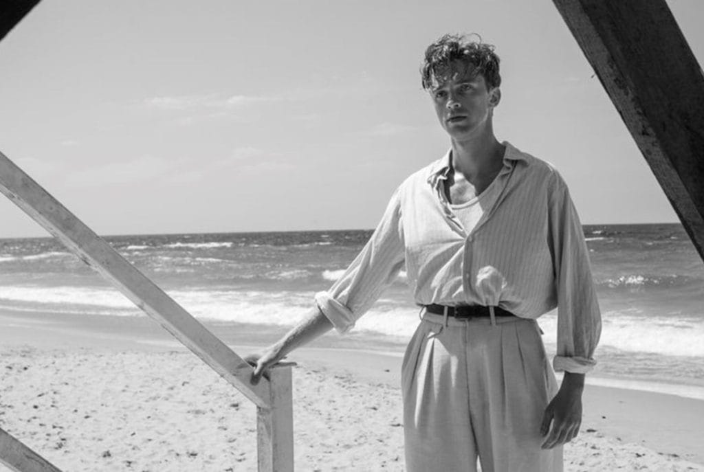 Crno bela fotografija, mladić na plaži, scena iz filma Stranac.