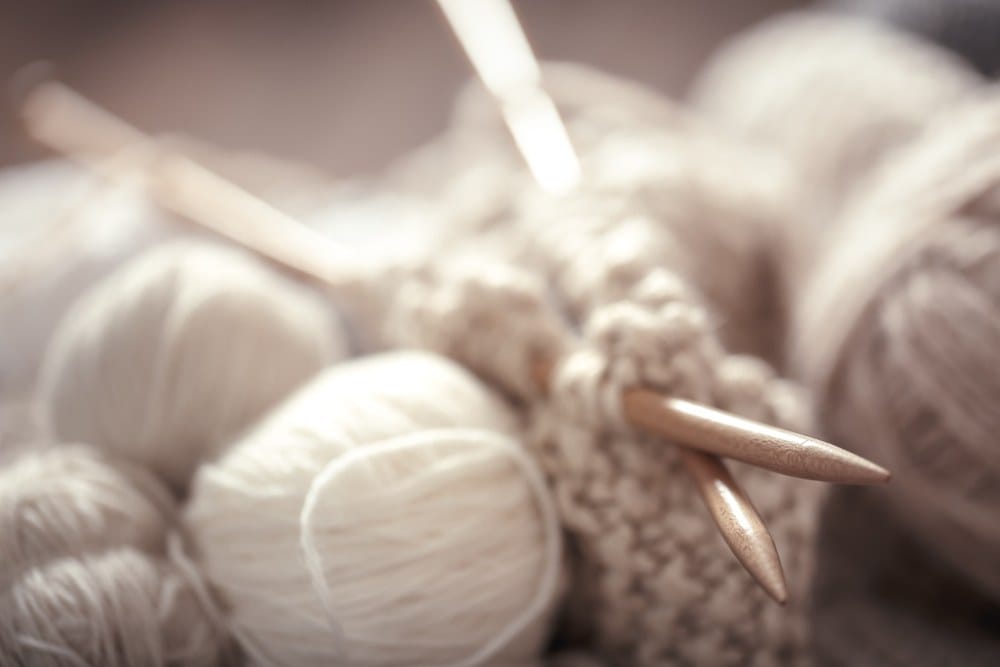 Klupko belo-bež vune. Započeto štrikanje i igle.