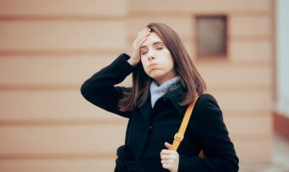 Žena na ulici se setila da je nešto zaboravila ili tako misli. Zatvorila je oči i stavila je ruku na glavu.