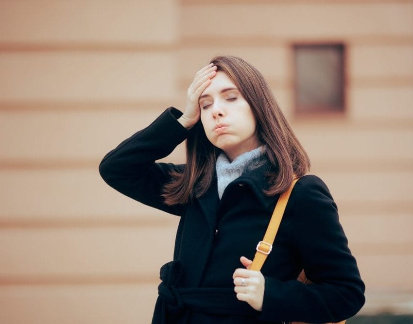 Žena na ulici se setila da je nešto zaboravila ili tako misli. Zatvorila je oči i stavila je ruku na glavu.