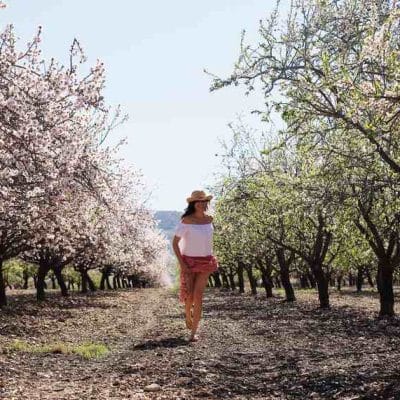Fit žena šeta kroz procvetali trešnjik.