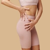 Žena nosi šorc/steznik za gornji deo butina i stomak.