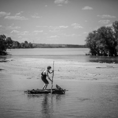 Crno bela fotografija, ;ovke plovi rekom na splavu.
