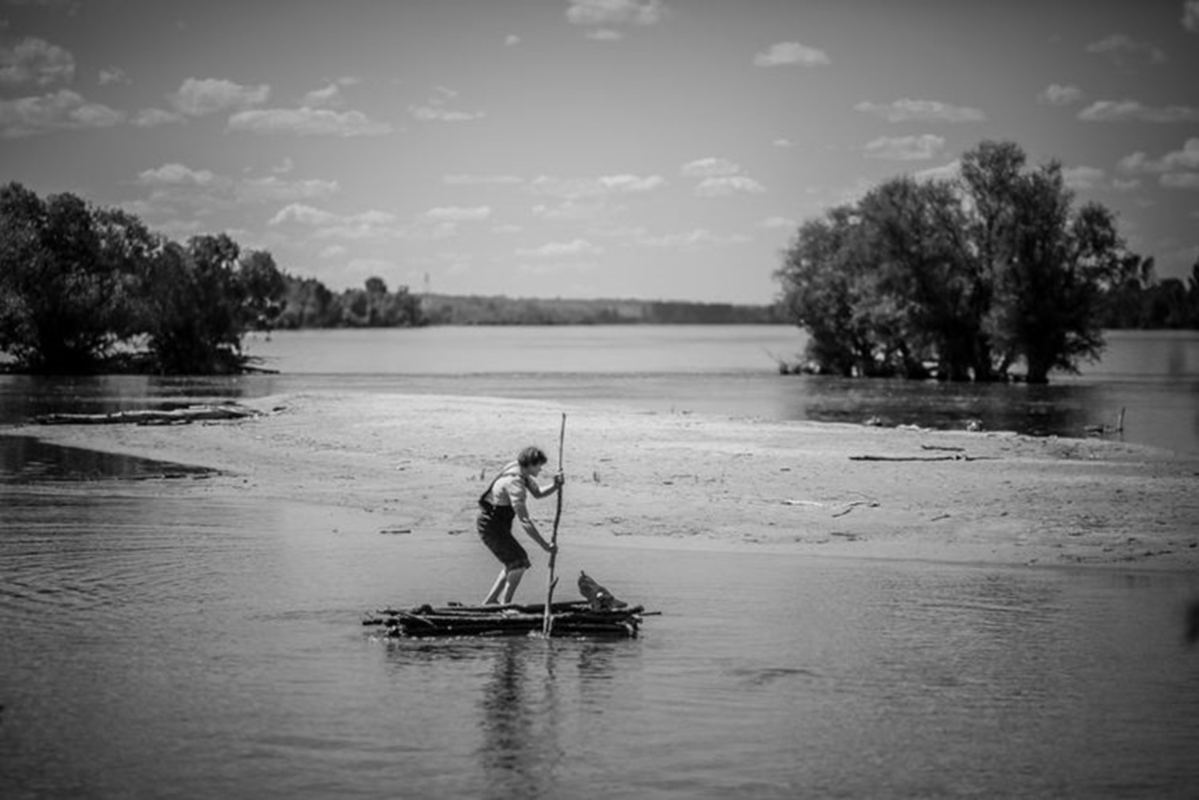 Crno bela fotografija, ;ovke plovi rekom na splavu.