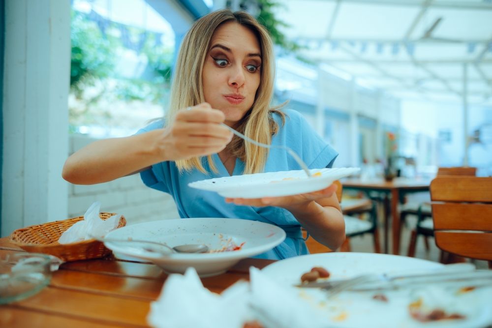 Žena raširenih očiju sa velikom požudom kao da prazni tanjire ispred nje, prejeda se. U tanjirima ništa ne ostaje.