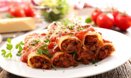 Kaneloni u tanjiru na stolu u pozadini se vidi čeri paradajz.
