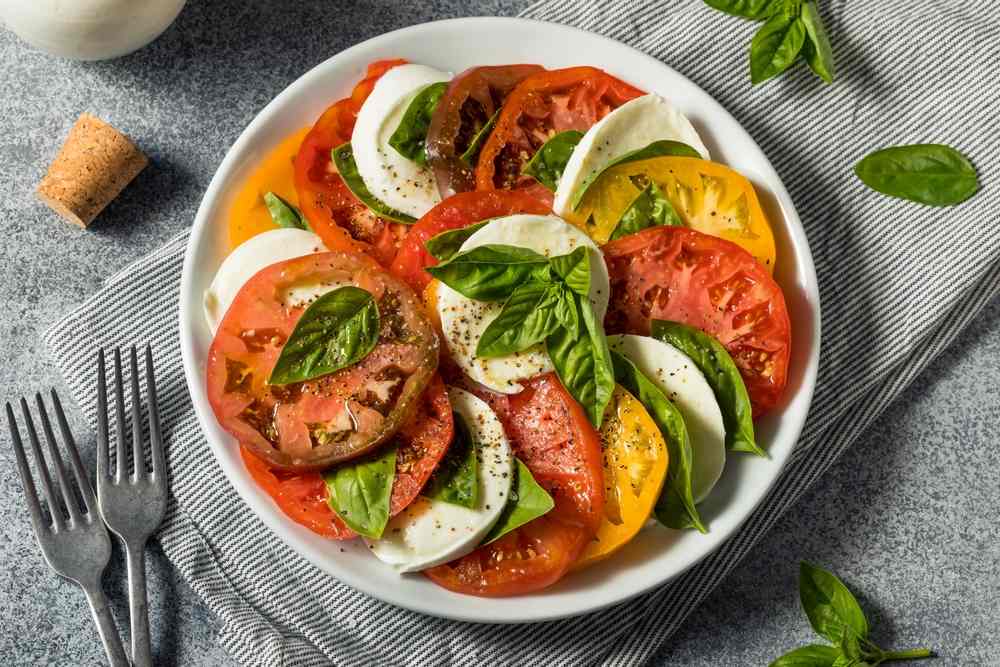 Kapreze salata u kojoj su kombinovani kolutovi paradajza raznih boja, crveni, crno-ljubičasti i žuti.