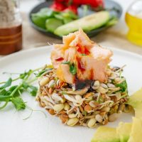 Salata od proklijalih semenki na kojoj su servirani komadi dimljene pastrmke.