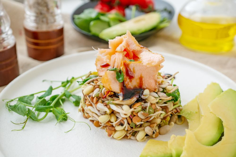 Salata od proklijalih semenki na kojoj su servirani komadi dimljene pastrmke.