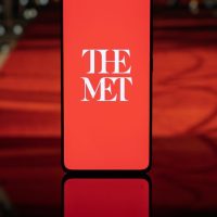 Natpis na ekranu mobilnog telefona The Met, belim slovima na crvenoj pozadini.