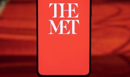 Natpis na ekranu mobilnog telefona The Met, belim slovima na crvenoj pozadini.