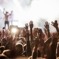 Muzi;ki koncet, scena, publika sa rukama podignutim u vazduh.