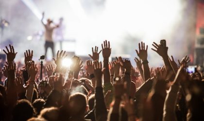 Muzi;ki koncet, scena, publika sa rukama podignutim u vazduh.