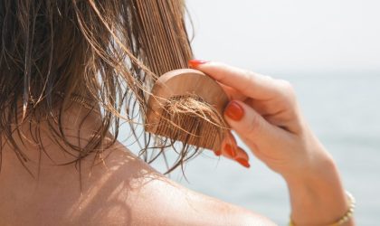 Žena na plaži raščešljava kosu nakon kupanja.