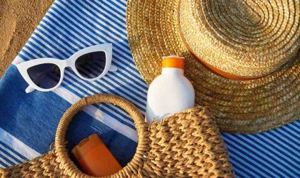 Razni rekviziti na plaži, naočare za sunce, šešir, krema za sunčanje.