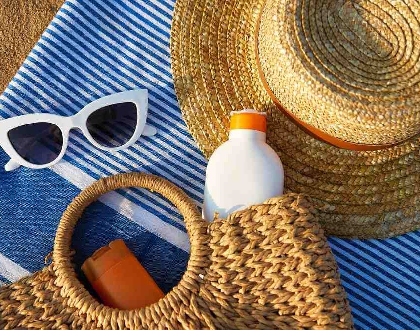 Razni rekviziti na plaži, naočare za sunce, šešir, krema za sunčanje.