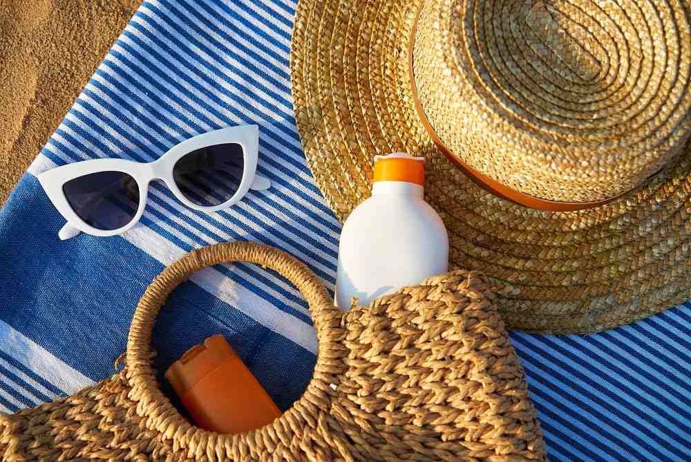 Razni rekviziti na plaži, naočare za sunce, šešir, krema za sunčanje.