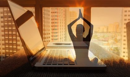 Fotografija ilustracija, lap top na stolu, kroz prozor se vidi grad. Preko fotografije je ilustracija žene koja radi jogu.