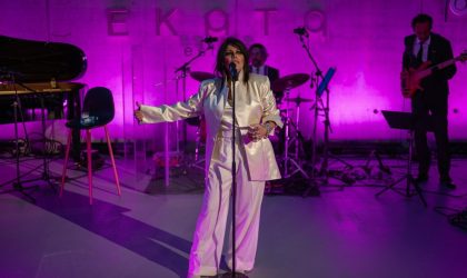 Yasmin Levi na bini u amfiteatru Ekata estate-a. U pozadini je ružičasto svetlo. Yasmin je u belom odelu.