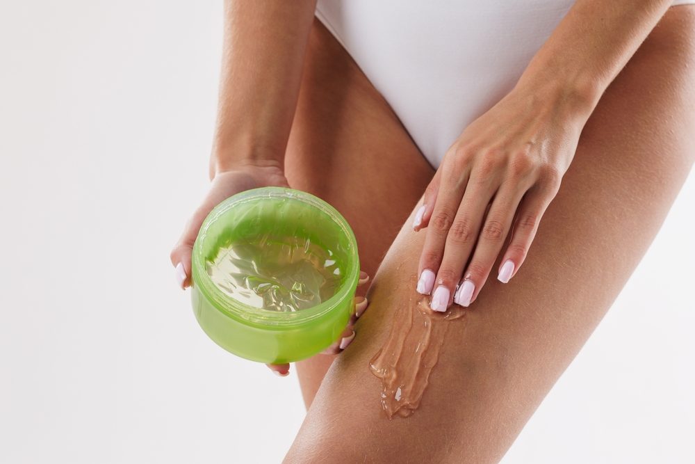 Devojka maže noge aloe vera gelom.