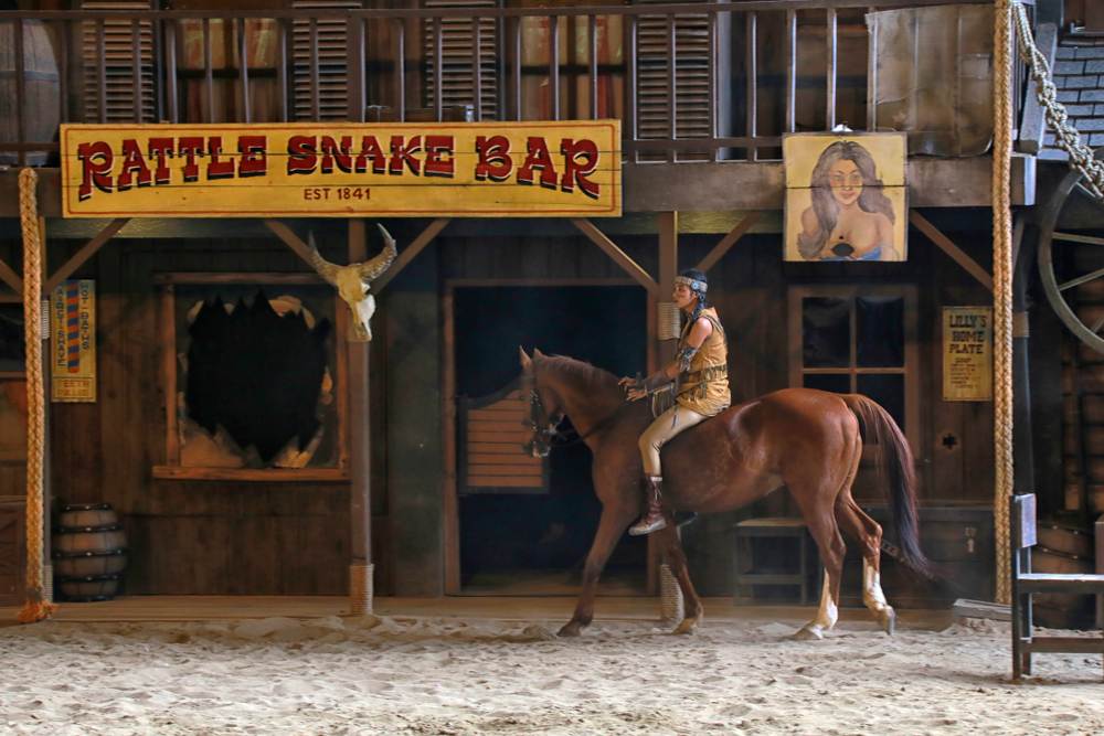 Indijanac u nekom od western filmova jaše. U pozadini se vidi kulisa za lokalni bar.