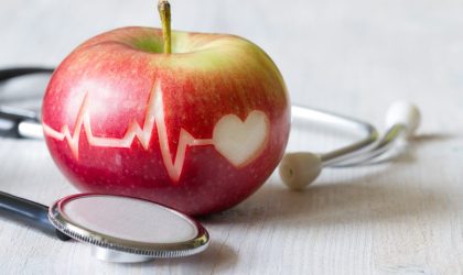 Jabuka na kojoj je urezana linija EKG-a i simbol srca. Na stolu pored jabuke je simbolično i stetoskop.