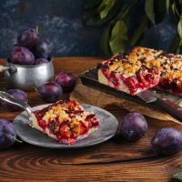 Na stolu je posluženje, kolač sa šljivama.