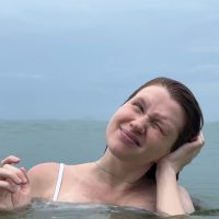 Devojka u moru, nagla je glavu na jednu stranu, leva ruka joj je na uhu.