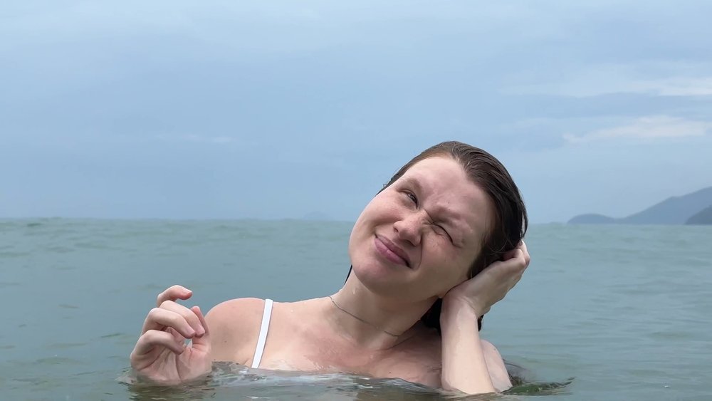 Devojka u moru, nagla je glavu na jednu stranu, leva ruka joj je na uhu.