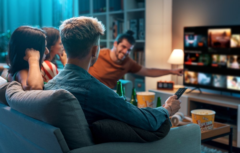 Društvo sedi i bira TV serije za gledanje na TV-u.