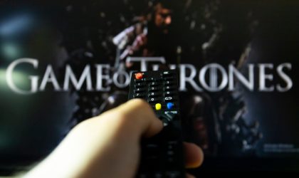 Na TV-u je špica za seriju Game of thrones. Daljinski upravljač u ruci, uperen ka TV-u.