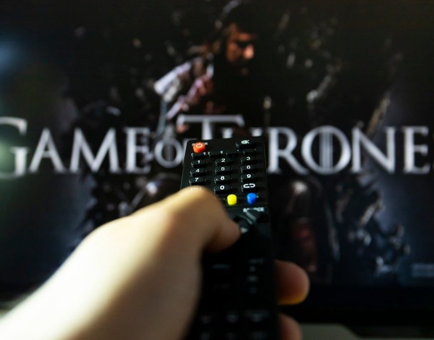 Na TV-u je špica za seriju Game of thrones. Daljinski upravljač u ruci, uperen ka TV-u.