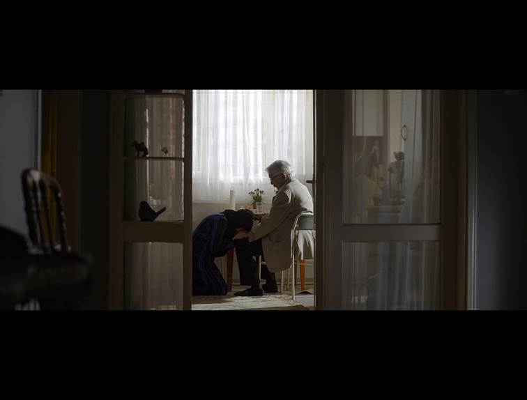 U dubini sobe se vidi čovek koji sedi, scena iz filma.